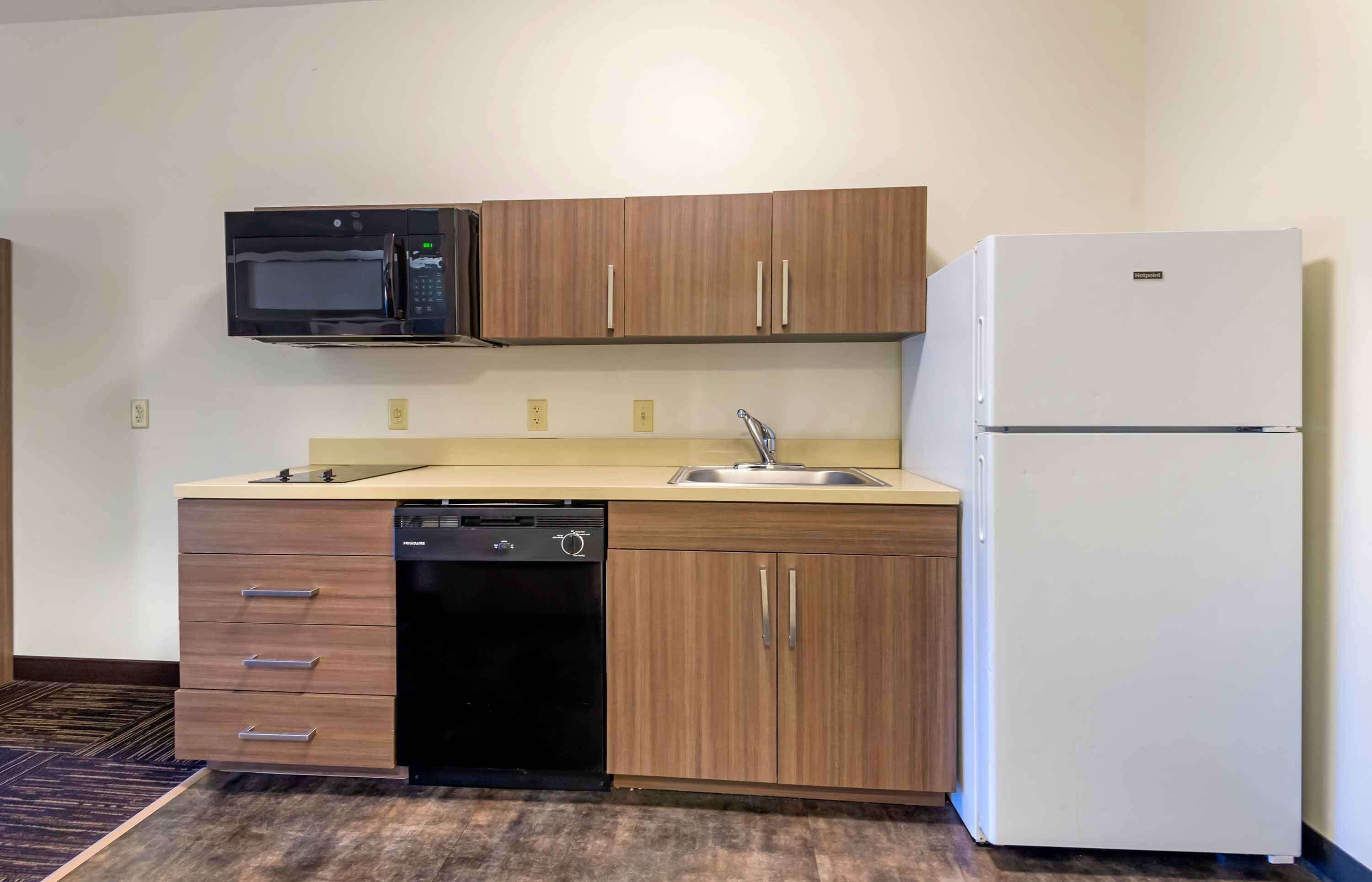 A compact kitchen with a microwave, dishwasher, sink, and refrigerator.