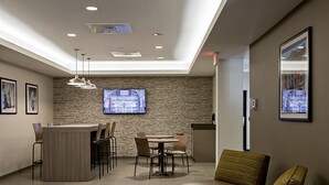 A modern waiting area with a reception desk, seating, and a large screen displaying a map. - Extended Stay America Suites Rock Hill (Rock Hill)