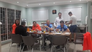 A dining area with a table set for a meal, chairs, and a person standing by the window. - The Musafer Travel Lodge (Pietermaritzburg)