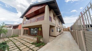 A two-story house with a balcony, a paved driveway, and a fenced backyard. - The Musafer Travel Lodge (Pietermaritzburg)