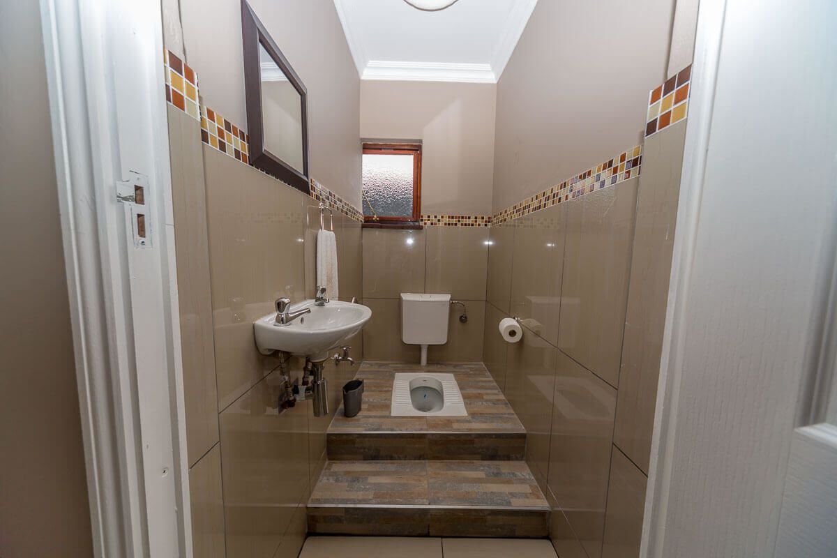 A compact bathroom with a sink, toilet, and steps leading to a window.