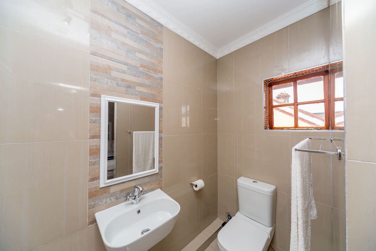 Ein Badezimmer mit Waschbecken, Spiegel, Toilette und einem Fenster mit Handtuchhalter.