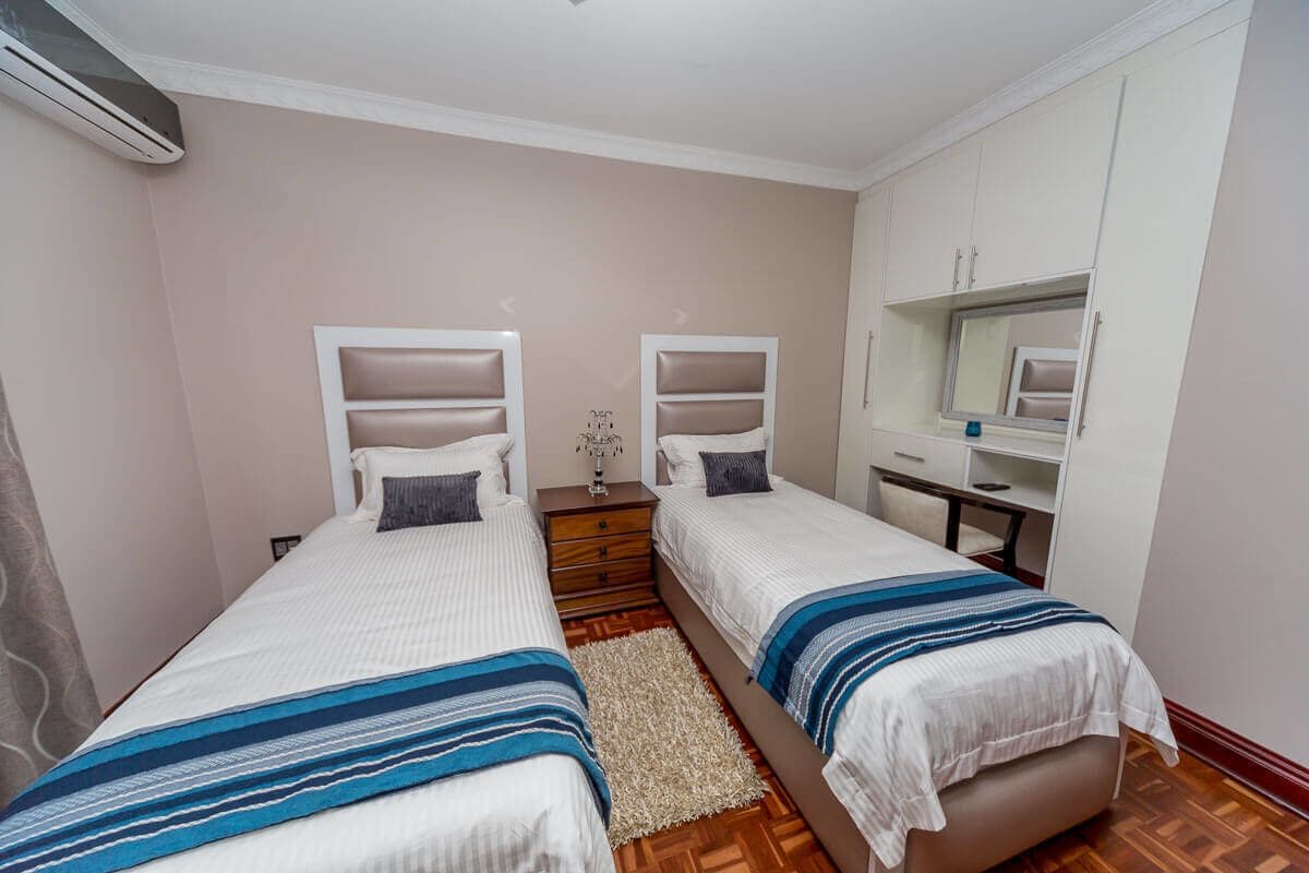 Un dormitorio con dos camas individuales, un aparador de madera, un espejo y una mesita.
