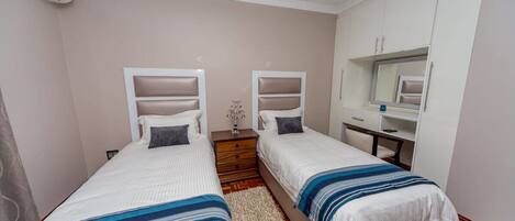Un dormitorio con dos camas individuales, un aparador de madera, un espejo y una mesita.