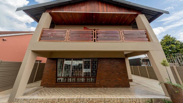A two-story house with a wooden facade, a brick entrance, and a herringbone-patterned floor. - The Musafer Travel Lodge (Pietermaritzburg)