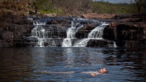 A waterfall with a person swimming in the water.