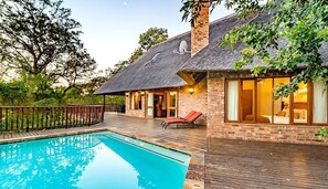 Une maison avec une piscine, une terrasse et une façade en briques.