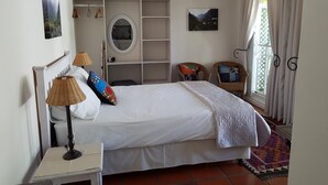 A bedroom with a bed, bedside lamps, a wardrobe, a mirror, and a window with curtains. - Sunny Lane (Franschhoek)