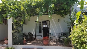 A covered patio with a table and chairs, steps leading to a door, and potted plants. - Sunny Lane (Franschhoek)