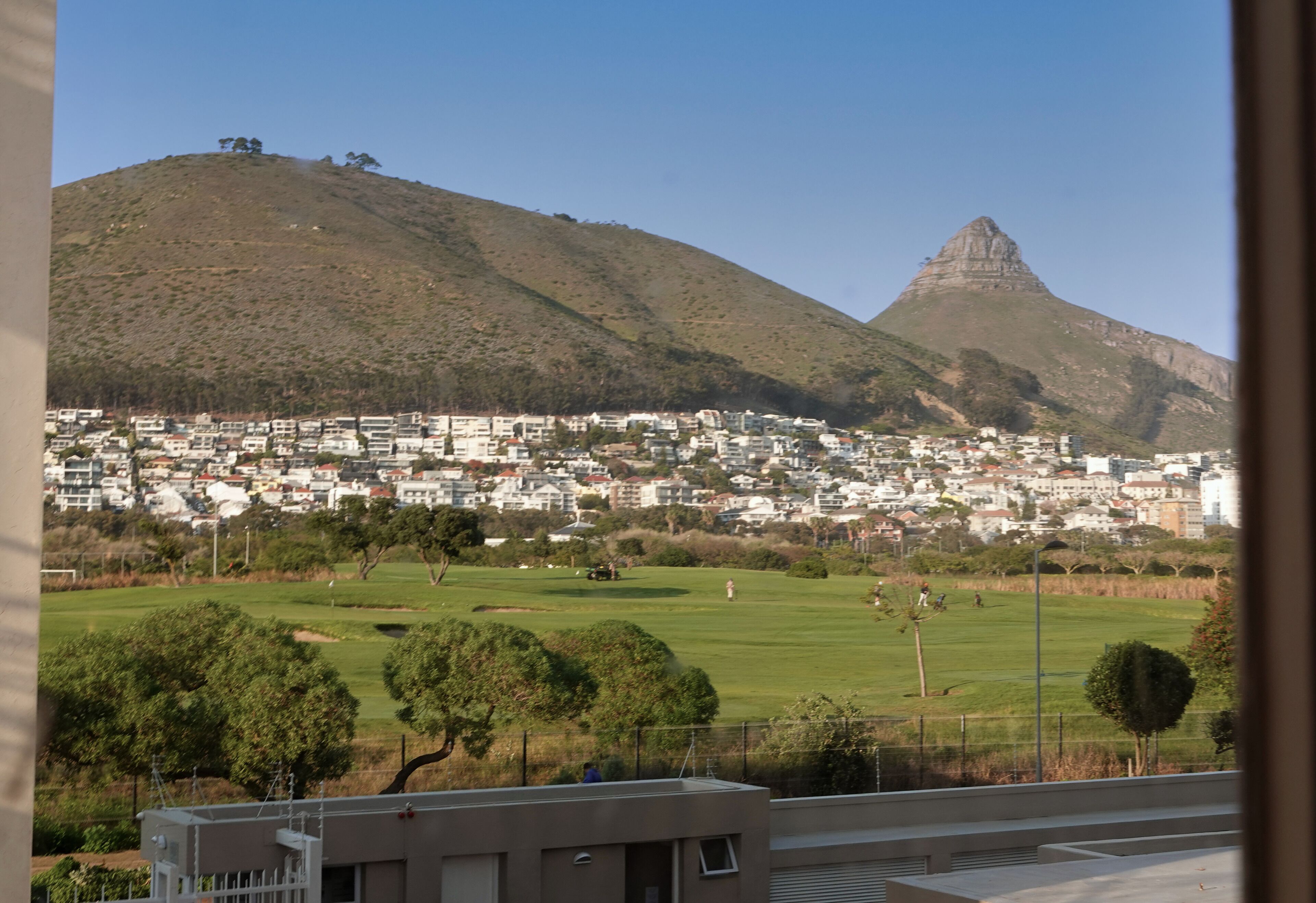 A residential area with houses, a hill, and a prominent mountain peak.
