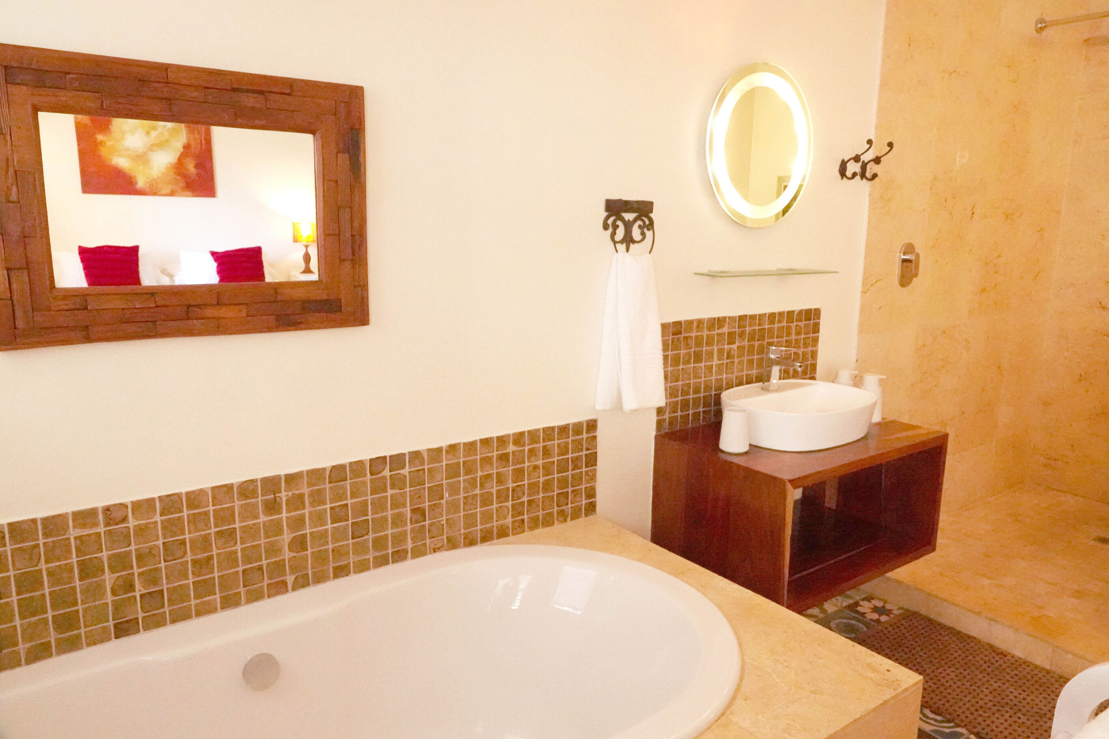 A bathroom with a large bathtub, a sink, a mirror, and a shower.