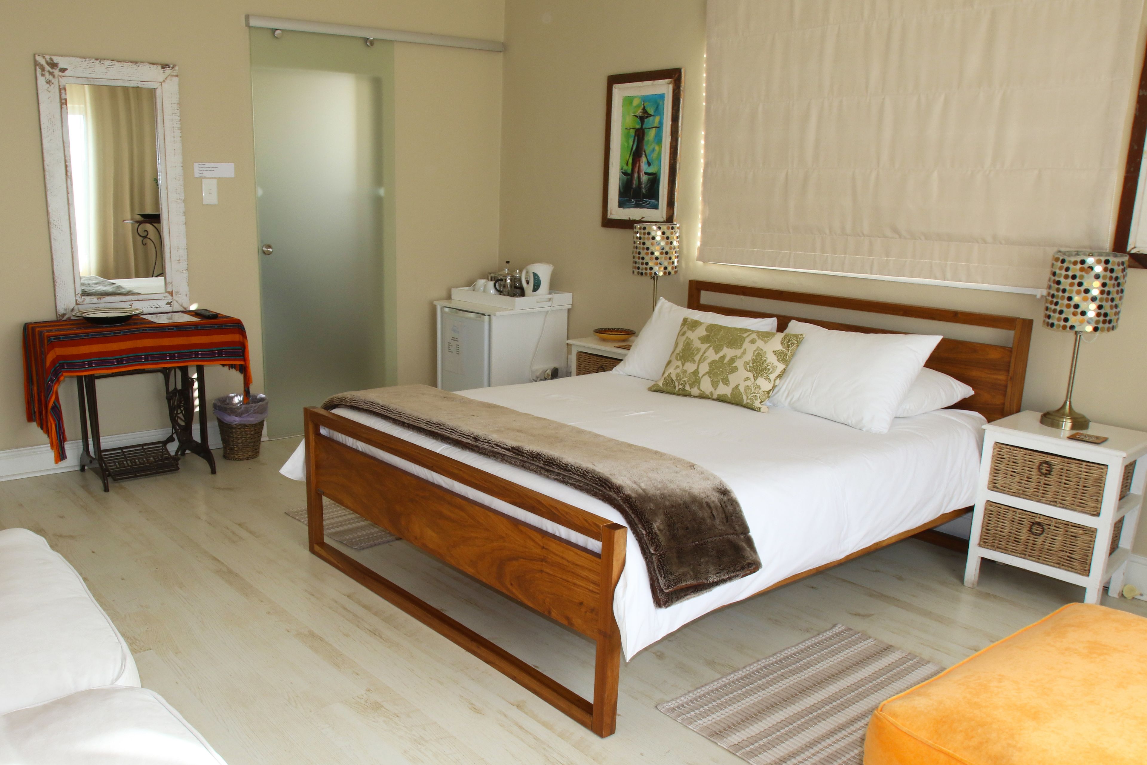 Une chambre à coucher avec un lit en bois, des tables de chevet, une commode, un miroir et un tableau accroché au mur.