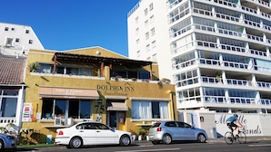 A building with a sign for 'Dolphin Inn Guesthouse' and '75 Beach Road'. - Dolphin Inn Guest House (Cape Town)