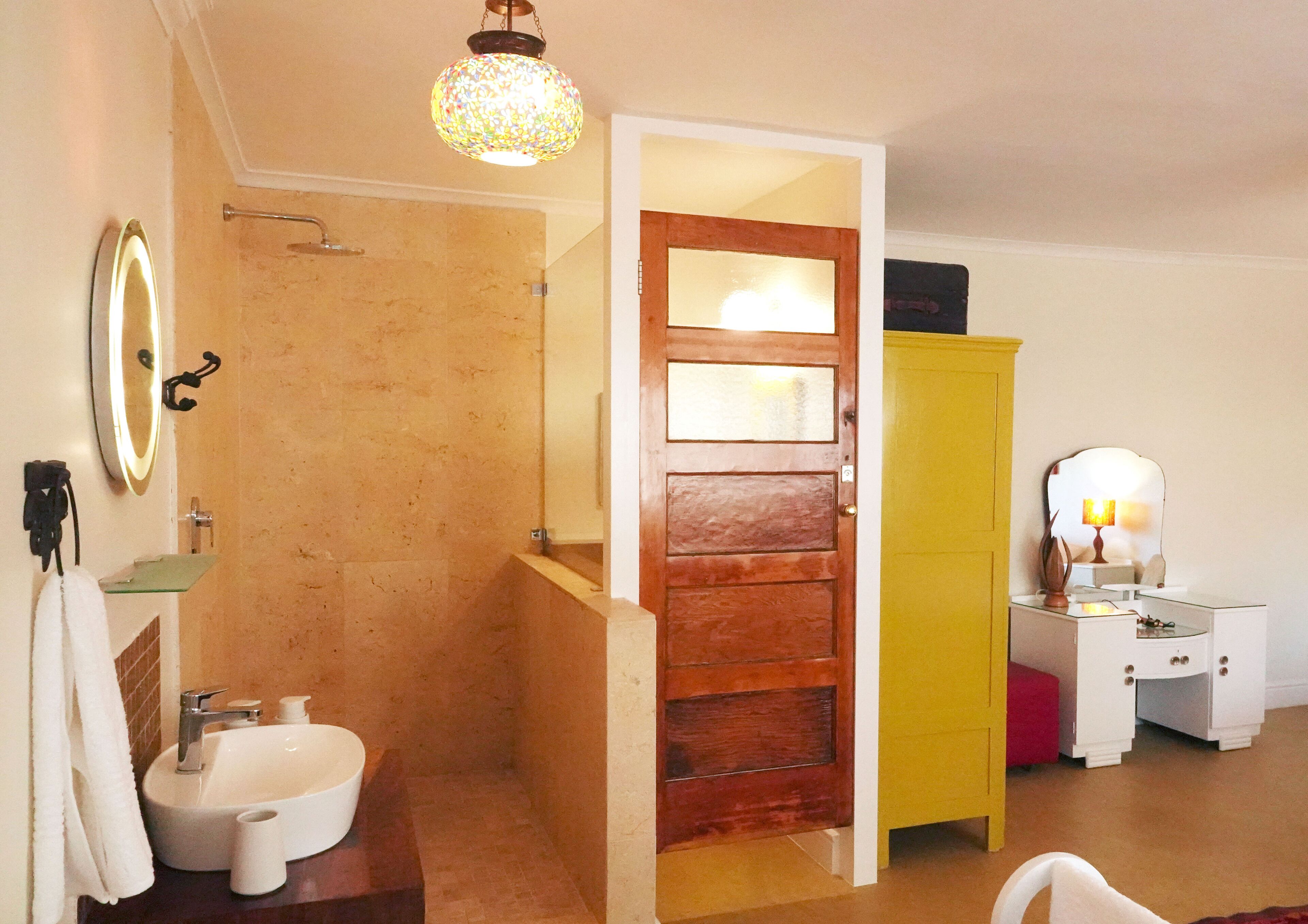 A bathroom with a sink, mirror, and a shower area.