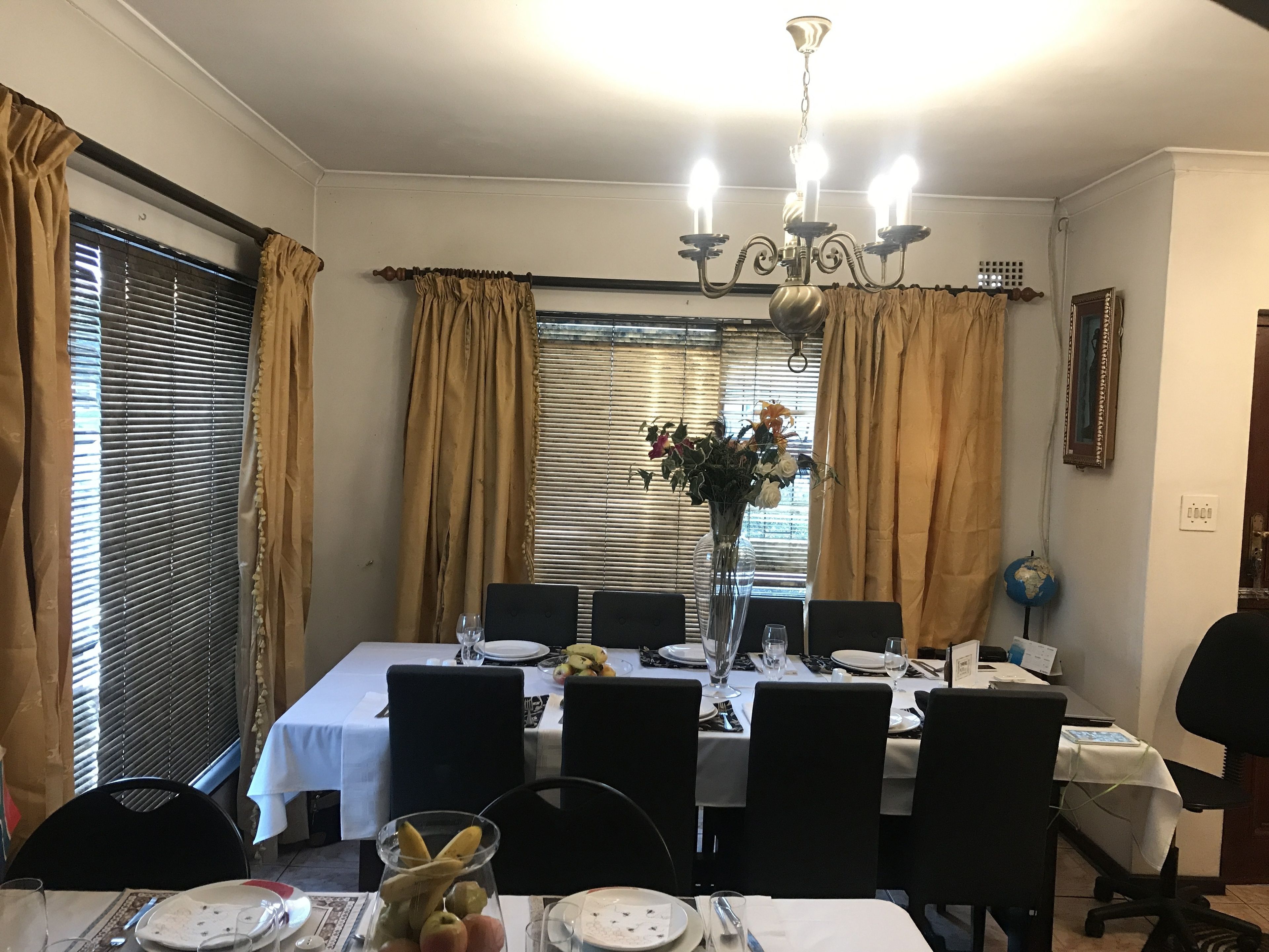 A dining area with a table set for six, including plates, glasses, and a vase with flowers.