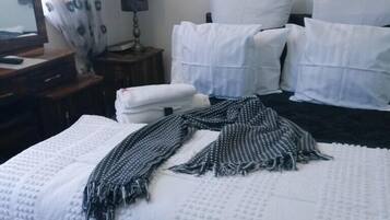 Habitación de hotel con cama, almohadas, una colcha, escritorio, espejo, lámpara y una bandera.