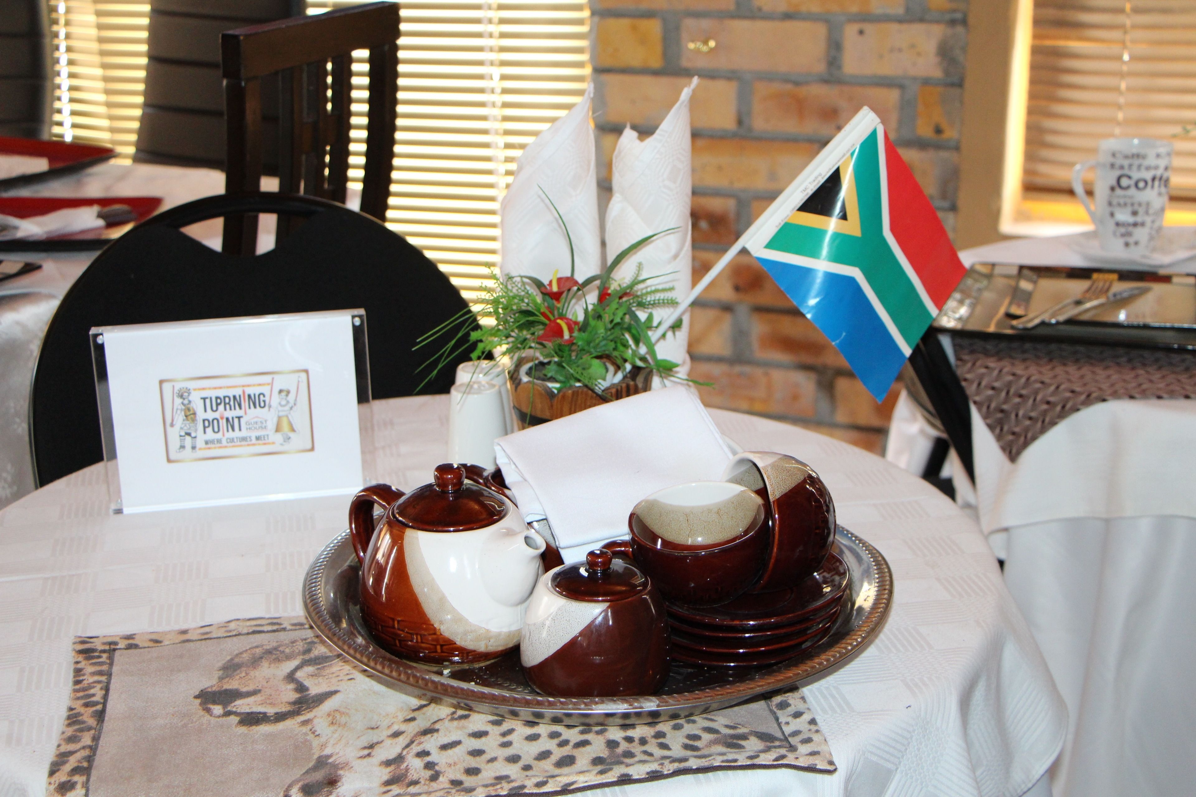 A table set with a tea set, a South African flag, and a sign indicating a tipping point.