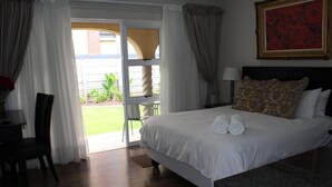A hotel room with a bed, a desk, a chair, and a view of the outdoors. - The Willow Tree Guest House (Klerksdorp)