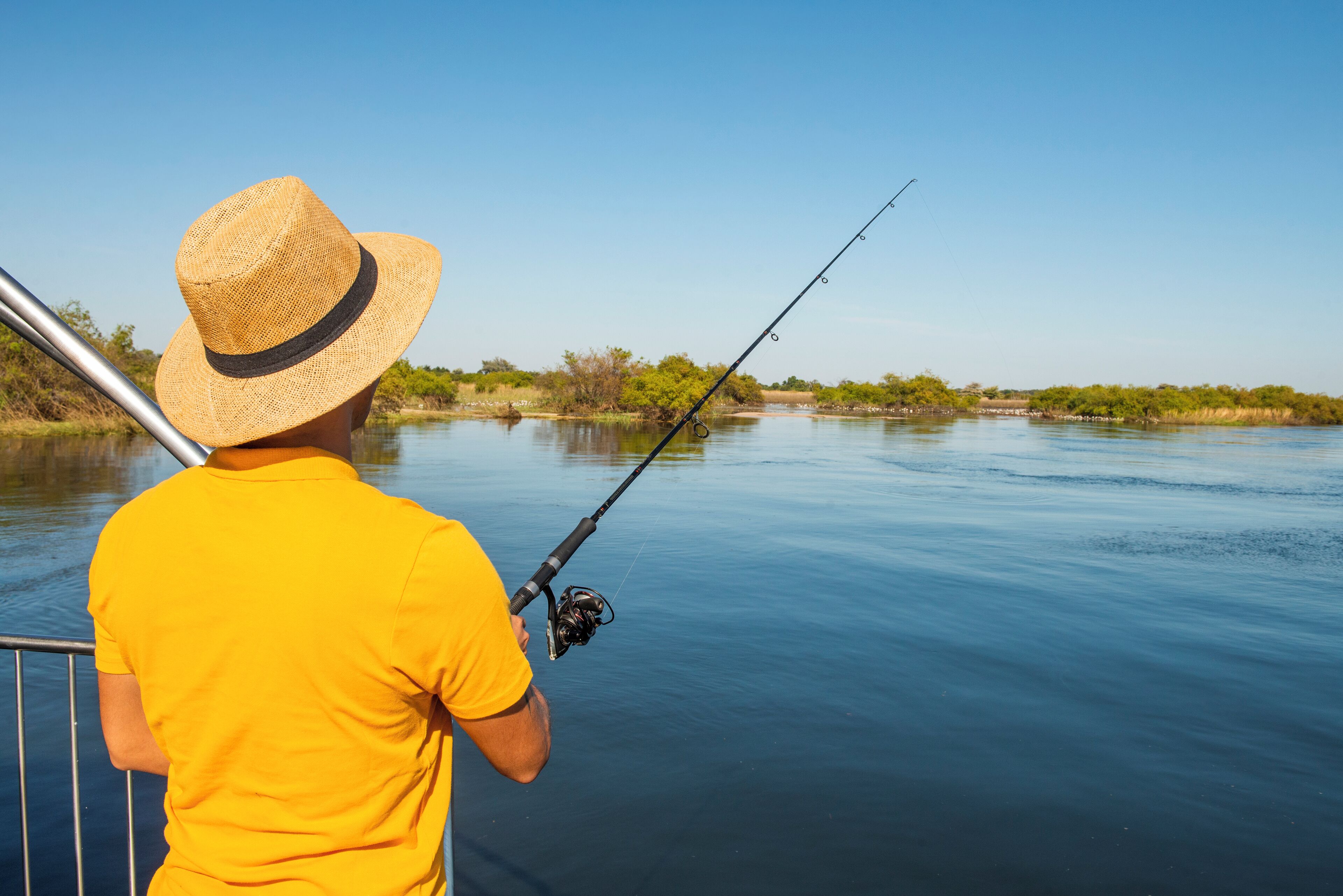 Una persona pescando junto a un río tranquilo.