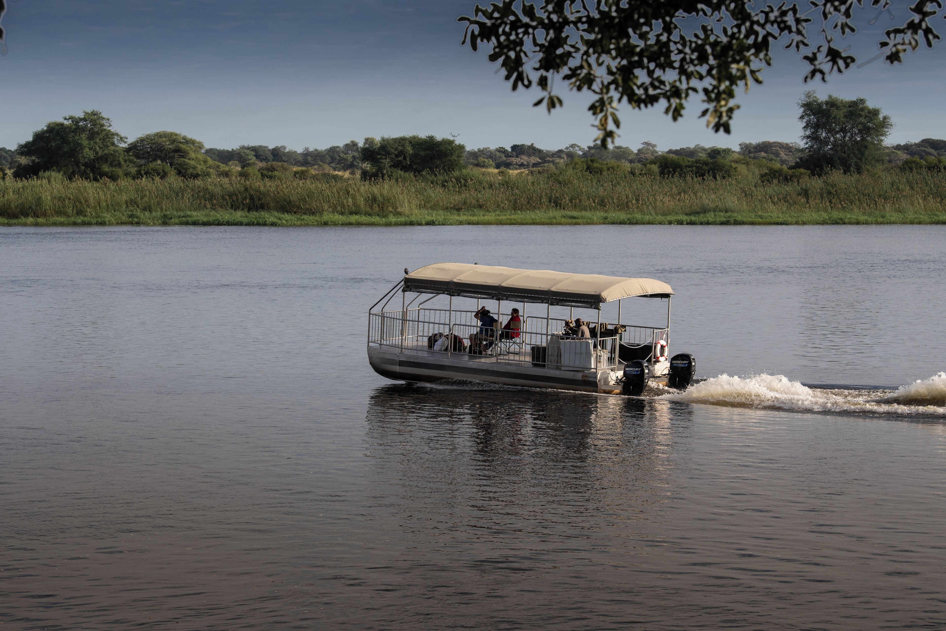A boat with passengers, moving on a calm body of water.