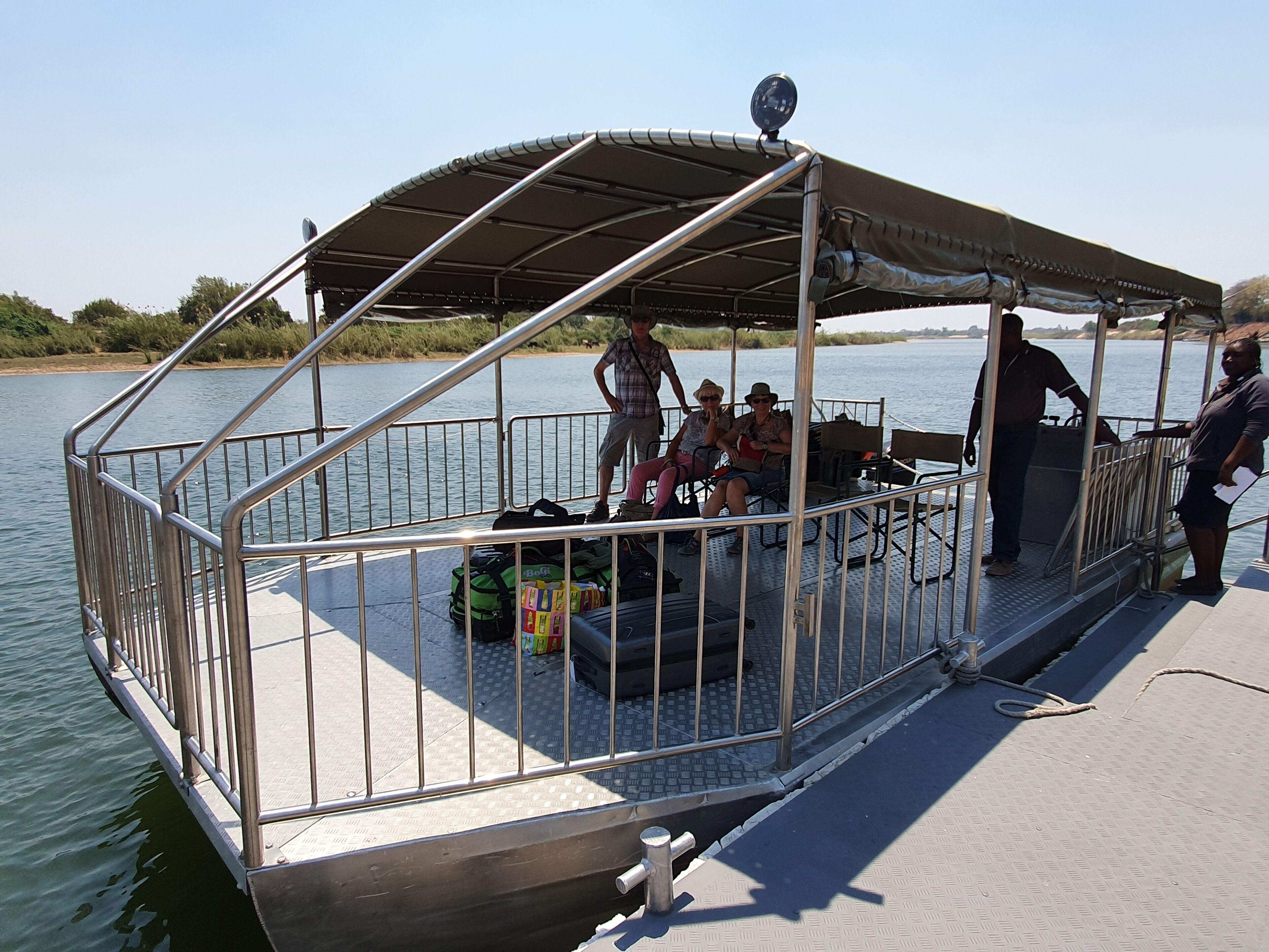 A covered boat deck with metal railings, a small covered seating area, and a person standing on the deck.