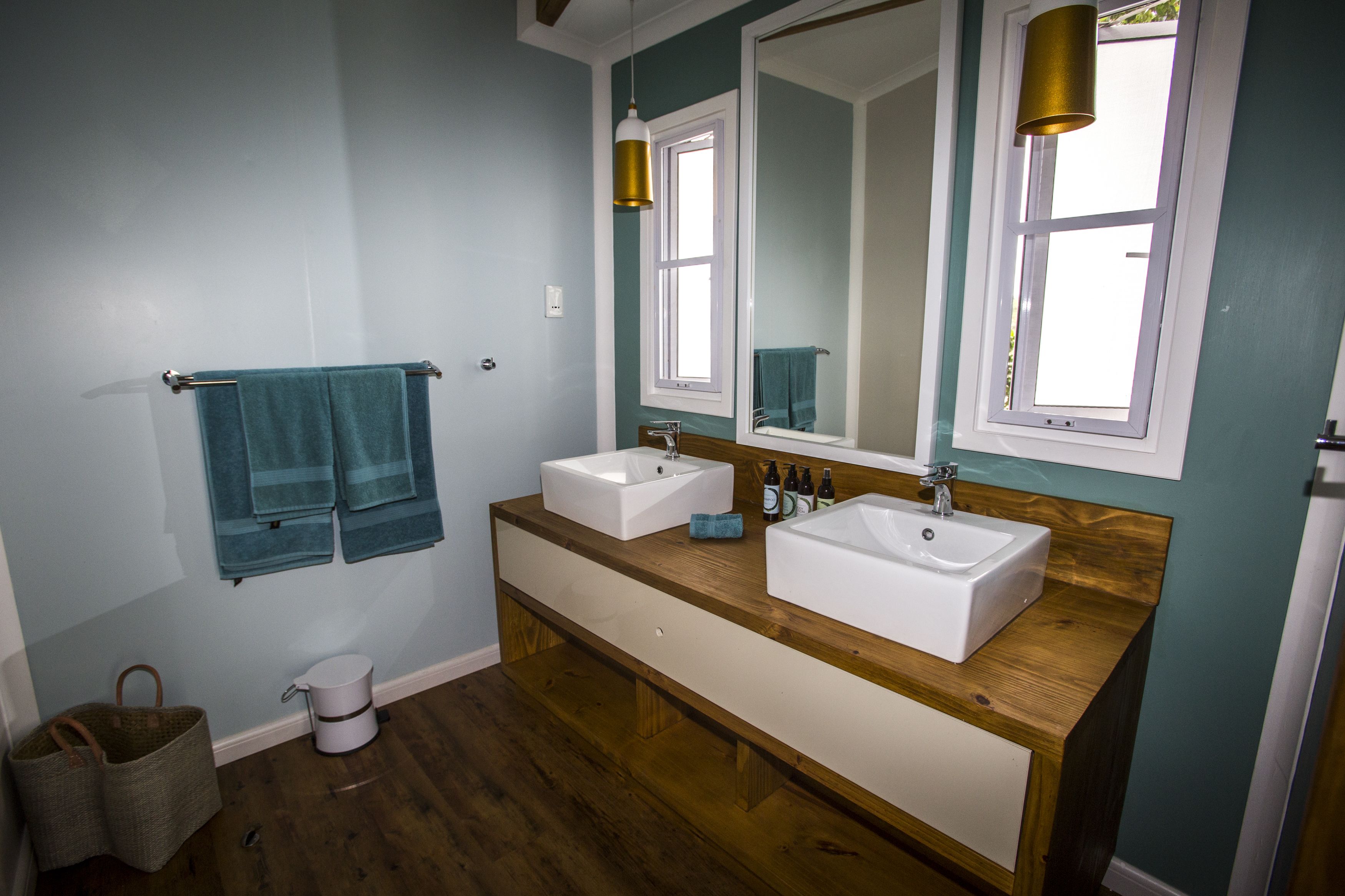 A bathroom with two sinks, wooden vanity, and a large mirror.
