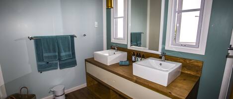 A bathroom with two sinks, wooden vanity, and a large mirror.