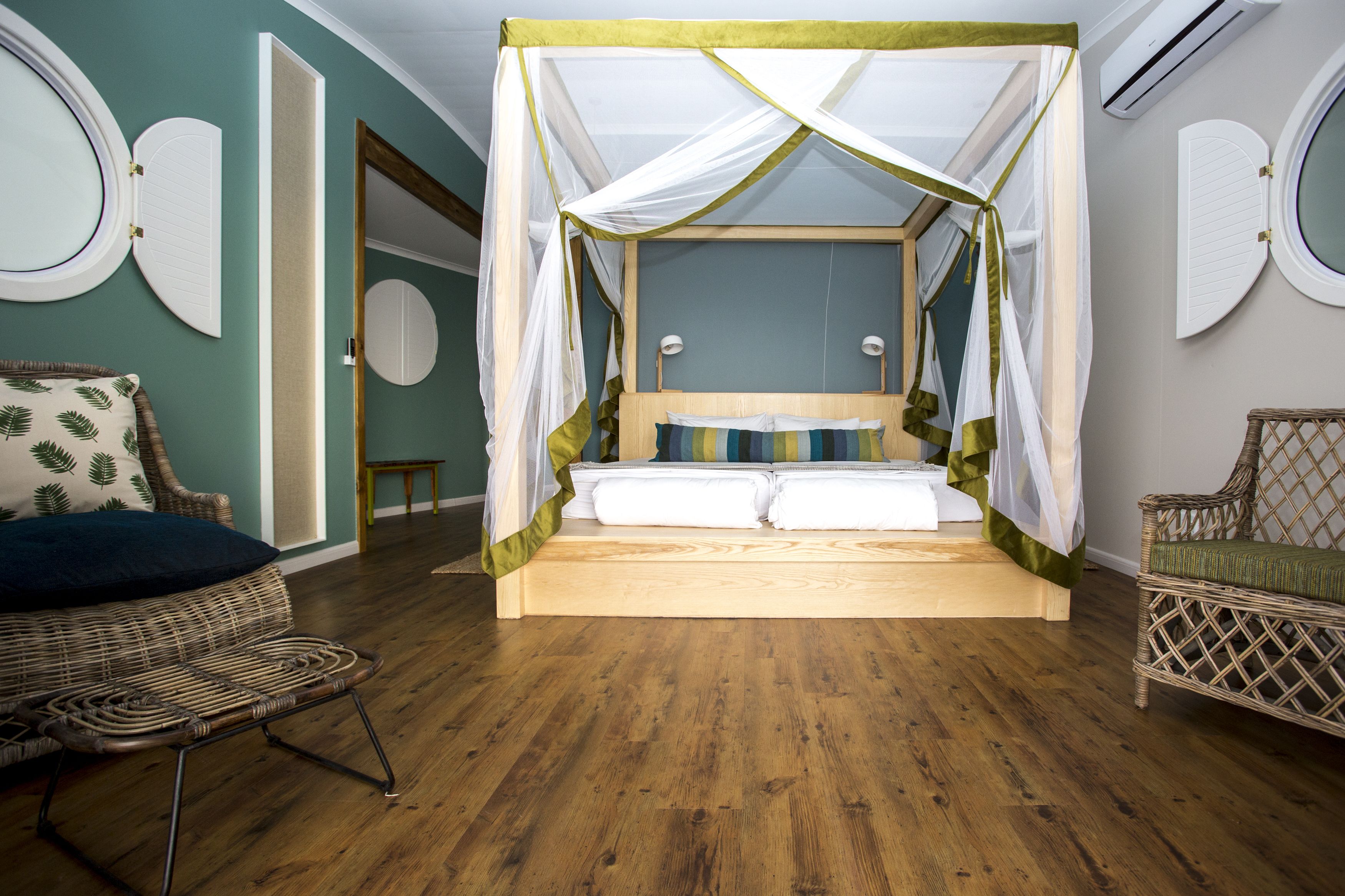 Une chambre dotée d’un lit à baldaquin, de meubles en osier et d’un plancher en bois.