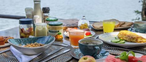 A breakfast table with various food items, a glass of orange juice, and condiments.
