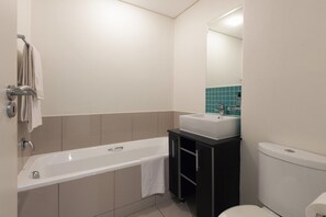 Un baño moderno con bañera, lavamanos e inodoro.