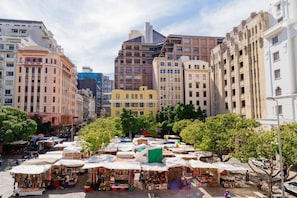 Un mercado al aire libre concurrido, con varios puestos y edificios históricos al fondo.