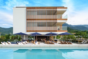 Um hotel moderno com piscina, espreguiçadeiras e guarda-sóis.