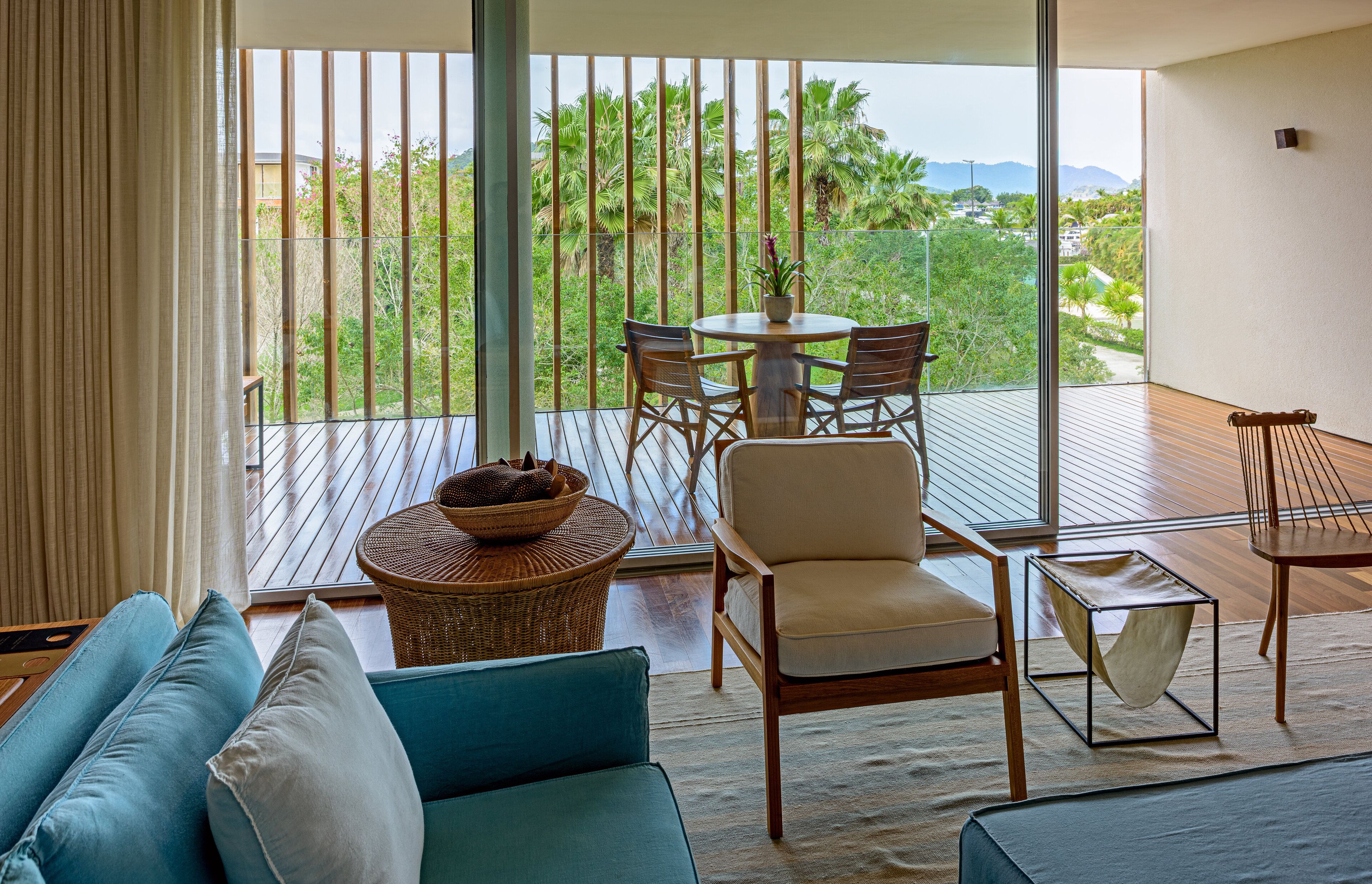 A balcony with a wooden table, chairs, and a wicker basket.