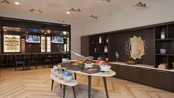 Eine moderne Hotelhalle mit Empfangsbereich, Sitzgelegenheiten und einem Frühstücksbuffet.