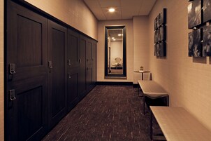 A hallway with dark wooden lockers, a bench, and a small table.