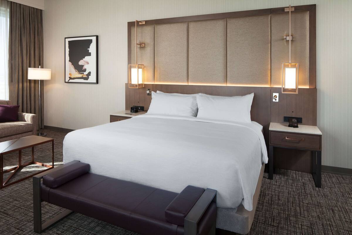 Une chambre d’hôtel avec un grand lit, deux tables de chevet, un bureau et une chaise.