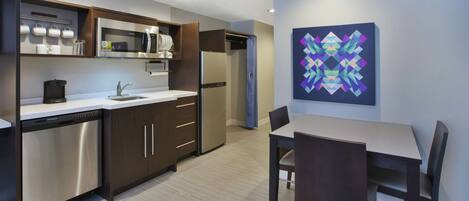 A modern kitchen with built-in appliances, a dining area with a table and chairs, and a decorative wall piece.