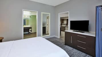 Ett hotellrum med en stor säng, en platt-TV, en byrå och ett badrum som syns genom en öppen dörr.