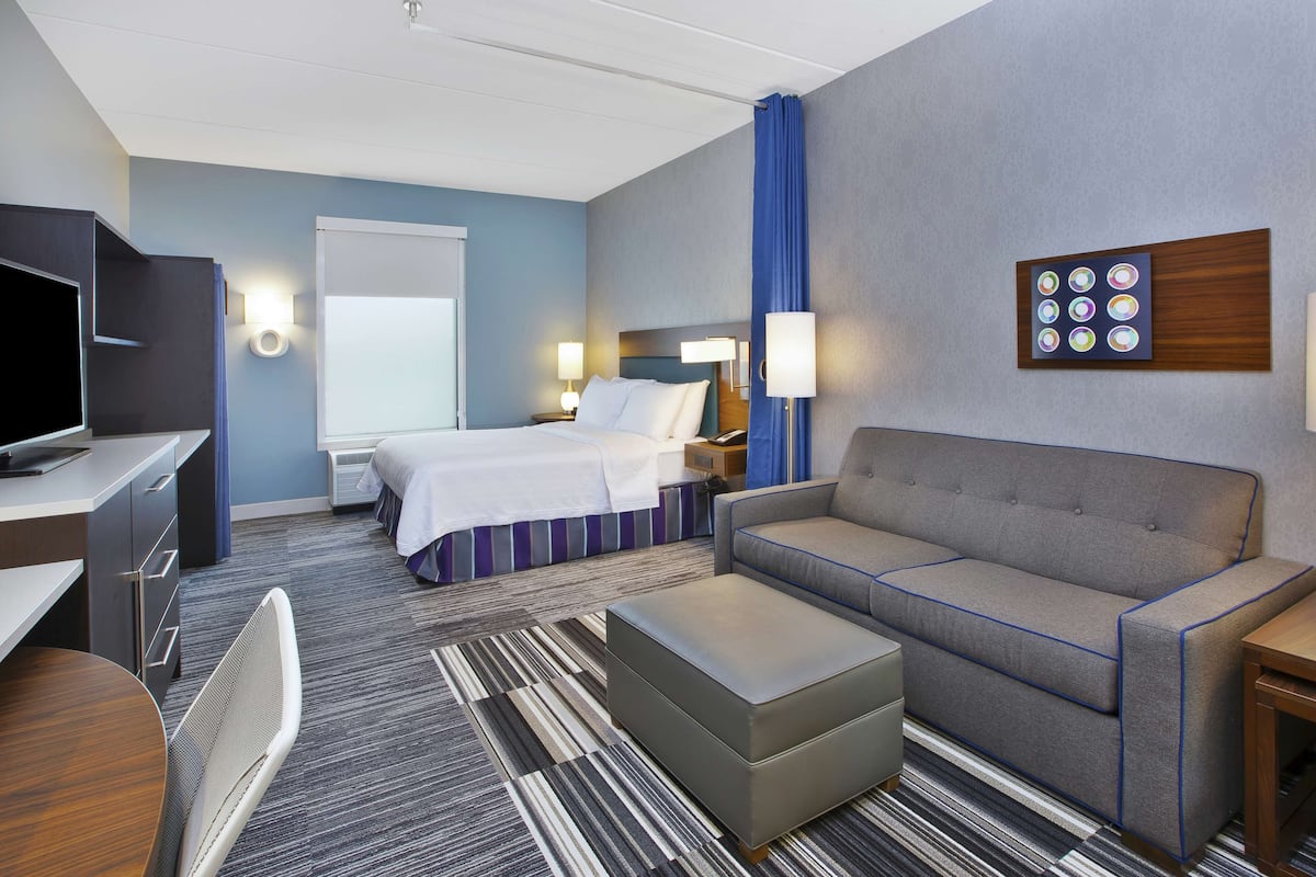 Een hotelkamer met een bed, een slaapbank, een televisie, een bureau en een nachtkastje.