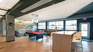 A pool table, bar area, and large windows in a modern indoor space.