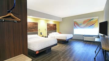 A hotel room with two beds, a wooden dresser, a desk, a television, and a large abstract painting on the wall.