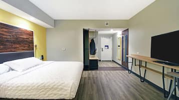 Una habitación de hotel con una cama, un escritorio, un televisor y un armario.