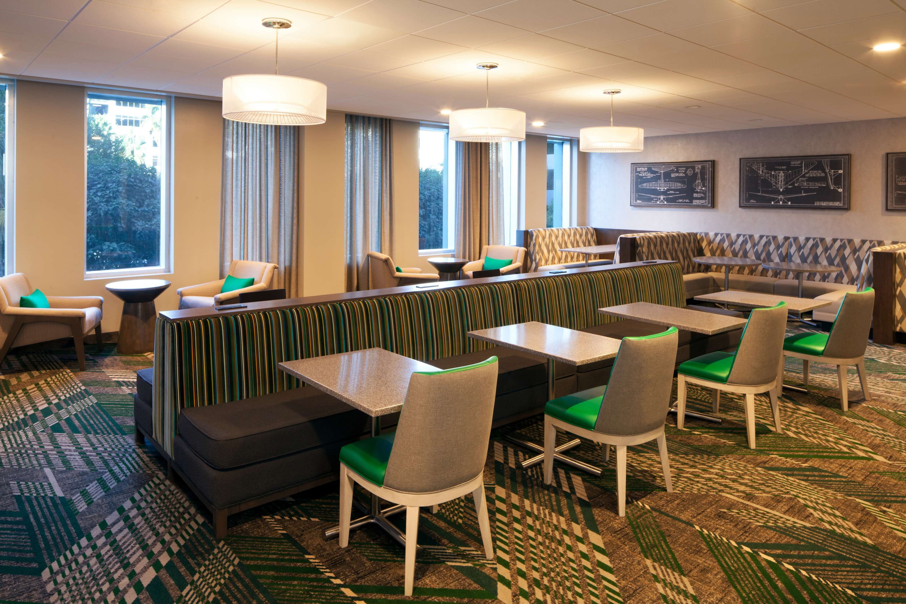 A modern restaurant with booths, high tables, and chairs.