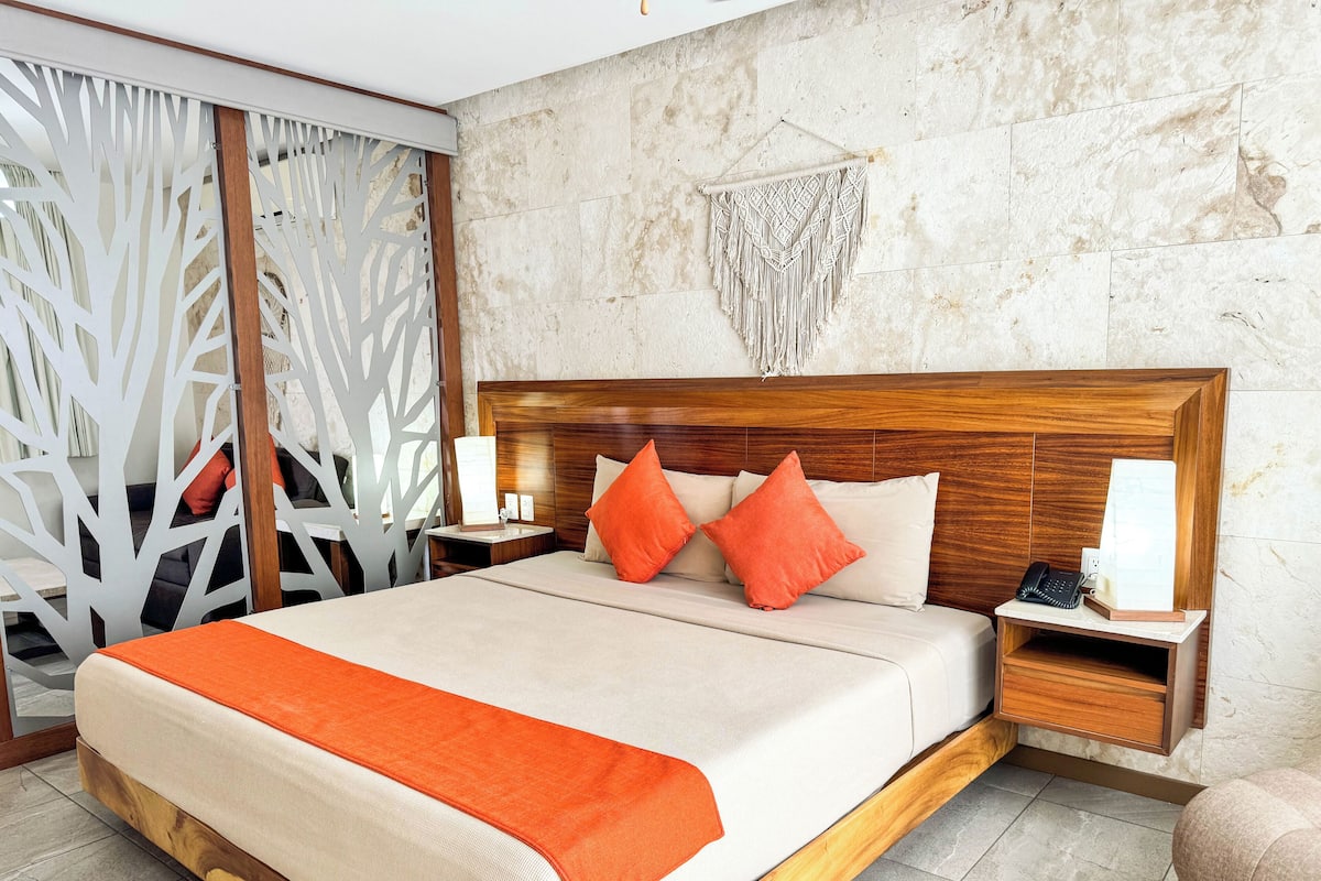 Een hotelkamer met een houten bed, twee nachtkastjes en een decoratieve wandversiering.
