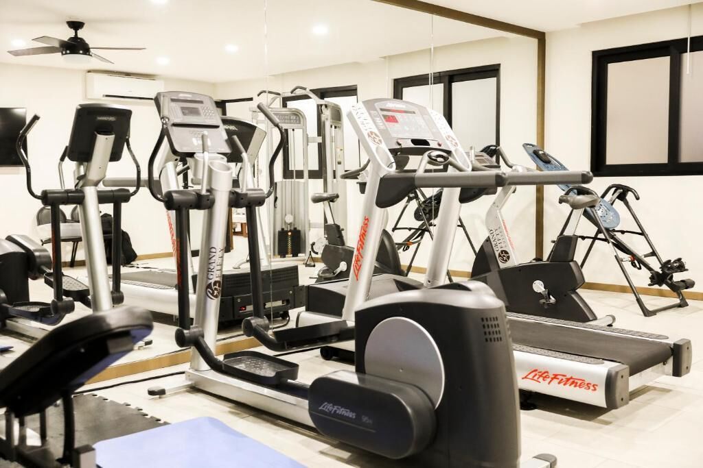 Un gimnasio con diversas máquinas de ejercicio, incluyendo cintas de correr y elípticas.