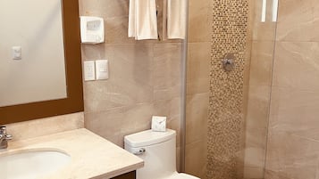 A modern bathroom with a glass-enclosed shower, a sink with a mirror, and a toilet.