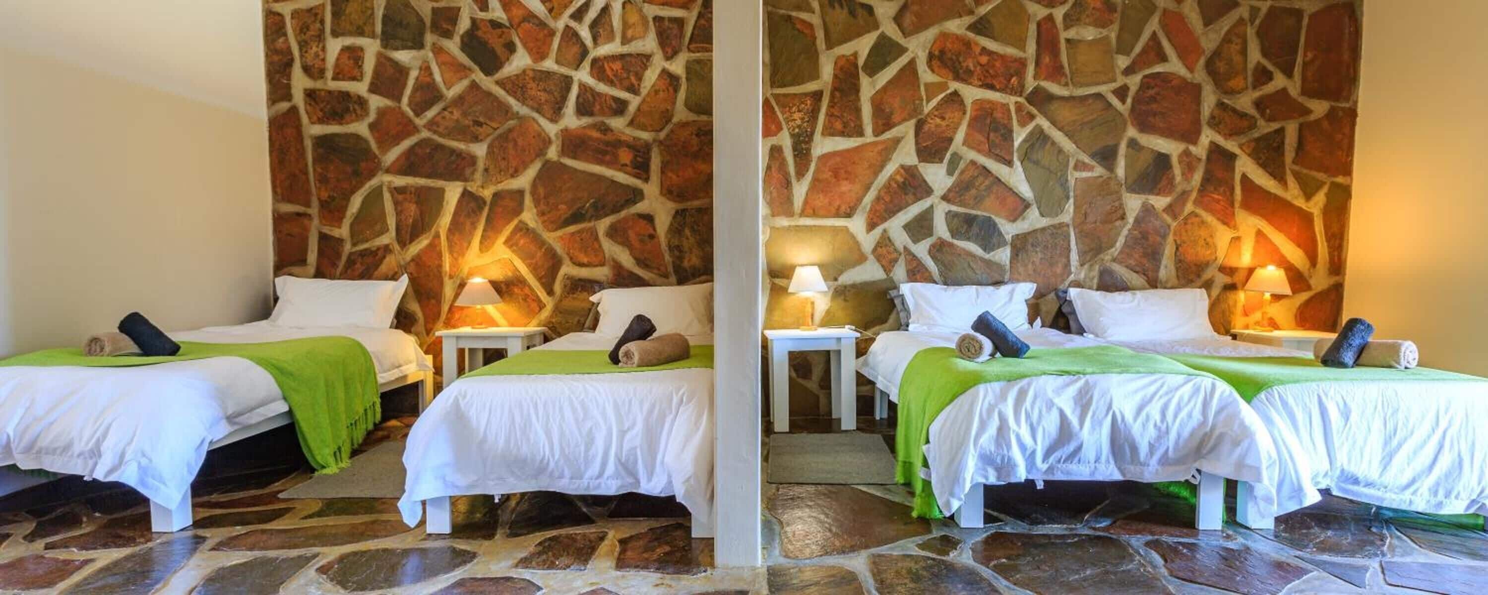 A hotel room with two beds, stone walls, and a stone floor.