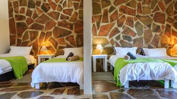 A hotel room with two beds, stone walls, and a stone floor.
