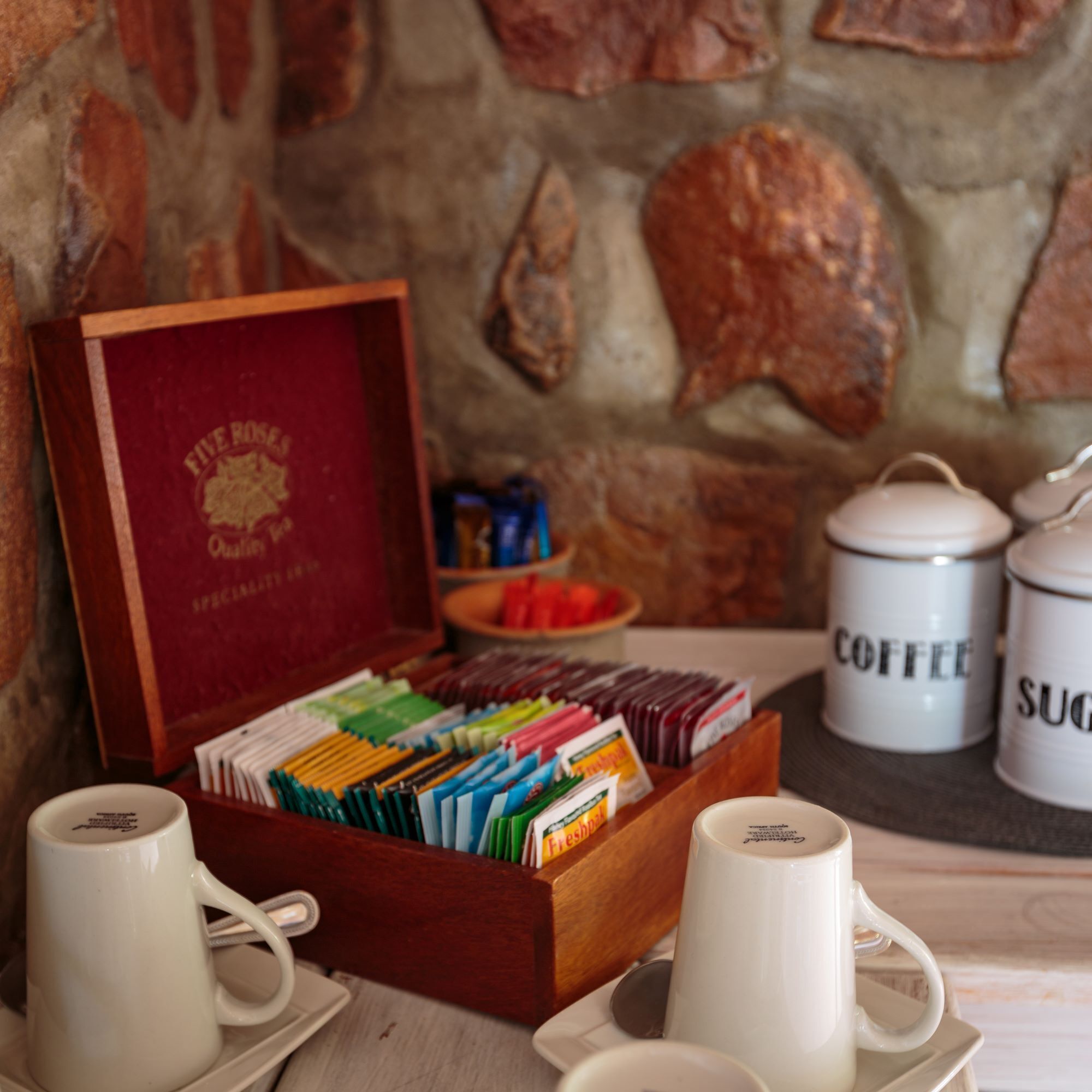 Una caja de madera con bolsitas de té, un juego de té y dos recipientes etiquetados como 