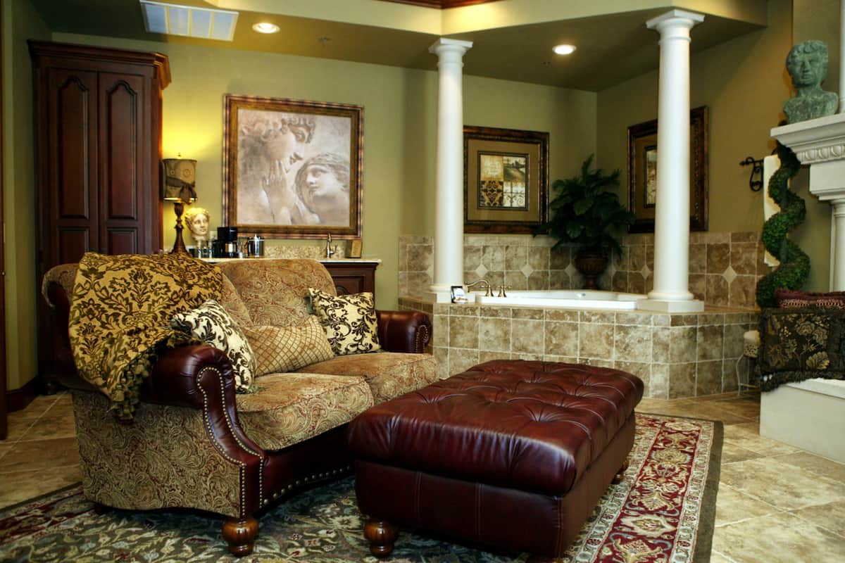 A living room with a sofa, ottoman, and a large painting on the wall.
